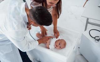 Young pediatrician is with little baby in the clinic at daytime photo