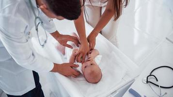 el joven pediatra está con un bebé en la clínica durante el día foto