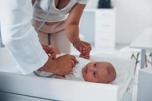 Young pediatrician is with little baby in the clinic at daytime photo