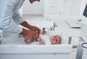 Young pediatrician is with little baby in the clinic at daytime photo