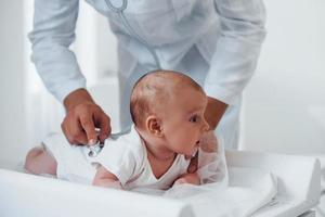 Young pediatrician is with little baby in the clinic at daytime photo