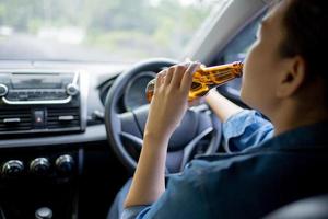 mujer joven bebiendo cerveza mientras conduce, accidente, no beba y conduzca el concepto. foto