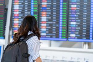 Woman tourist checking flight time table on board in airport. With copy space photo