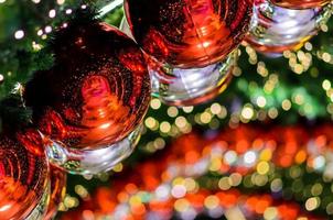 Red bauble and other ornament hanging on Christmas tree with bokeh light background. photo