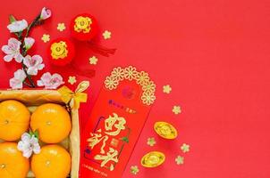 Flat lay of Chinese new year festival decoration on red background. Character on ingot means Blessing on money red packet means Good omens. photo