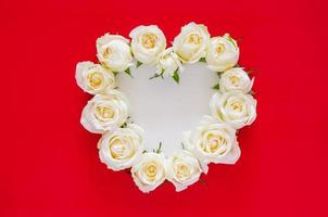 White roses put as heart shape on red background with white space for text for Valentine day. Flat lay background concept. photo