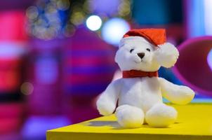 Selective focus on Santa claus teddy bear eyes who wearing hat sitting in front of colorful blurred background and bokeh lights. photo