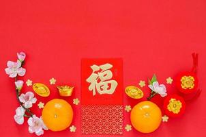 Flat lay of Chinese new year festival decoration on red background. Character on ingot and money red packet means Blessing. photo
