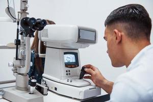 El oculista prueba la visión del paciente mediante el uso de una máquina moderna especial foto