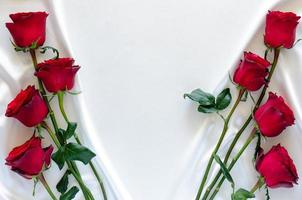 rosas rojas puestas sobre fondo de tela satinada blanca para el concepto de aniversario, madre y día de san valentín. foto