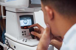El oculista prueba la visión del paciente mediante el uso de una máquina moderna especial foto