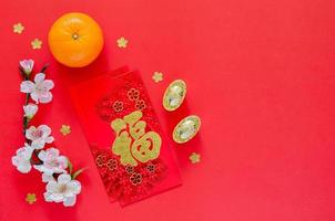 Red envelope packets or ang bao word means wealth with gold ingots, orange and Chinese blossom flowers for Chinese new year on red background. photo