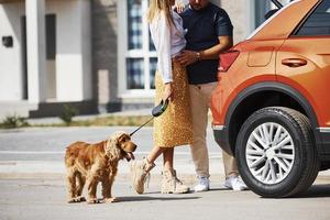 Lovely couple have a walk together with dog outdoors near the car photo