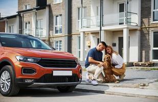 Lovely couple have a walk together with dog outdoors near the car photo