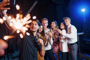 Takes selfie. Group of cheerful friends celebrating new year indoors with drinks in hands photo