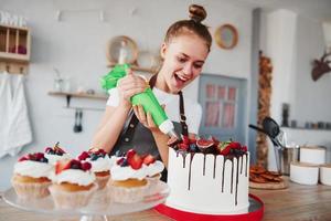 Pouring cream. Woman stands indoors in the kitchen with homemade pie photo