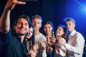 Group of cheerful friends celebrating new year indoors with drinks in hands photo
