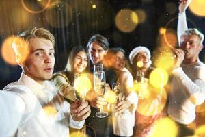 grupo de jóvenes alegres tienen fiesta y celebran el año nuevo en el interior foto