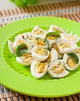 Boiled quail eggs halves on a green plate photo