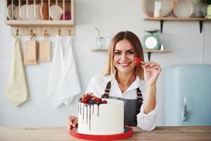 Positive blonde in indoors with her homemade pie holds fruit photo