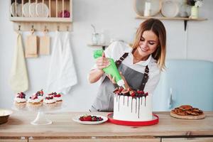 Pouring cream. Woman stands indoors in the kitchen with homemade pie photo