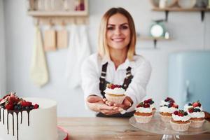 Positive blonde with her homemade delicious cookies and cake in the kitchen photo