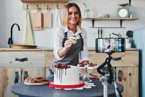 Woman makes delicious sweets and pie. Recording process by smartphone on tripod photo