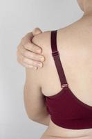 woman in a sports bra holding her sore shoulder, stretched tendons of the forearm photo