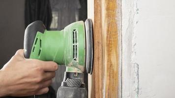 hand worker sanding a wooden doorway with a grinder photo