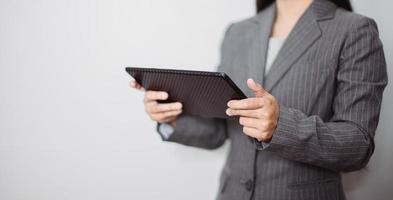 Asian businesswoman working at home using tablet device, browsing internet playing social media in video call meeting with colleagues and coworkers planning innovative ideas, quarantine self-isolation photo