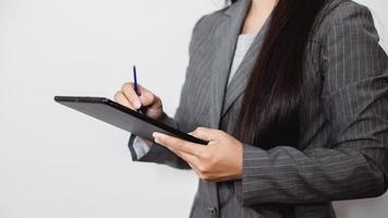 Asian businesswoman working at home using tablet device, browsing internet playing social media in video call meeting with colleagues and coworkers planning innovative ideas, quarantine self-isolation photo