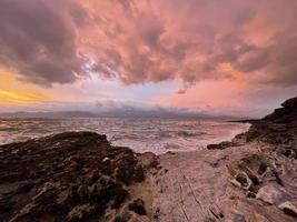 un amanecer con una variedad de colores salvajes y hermosos en el famoso punto penmon en el norte de gales