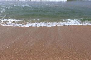 Ocean shore with sandy beach and advancing wave photo