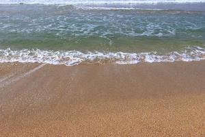 Ocean shore with sandy beach and advancing wave photo