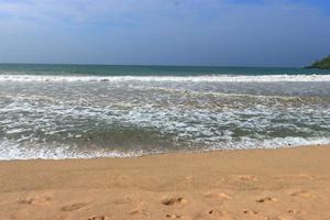 Ocean shore with sandy beach and advancing wave photo