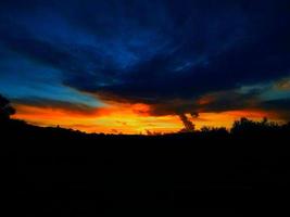 puesta de sol de color rojo anaranjado con nubes de tonos azules foto
