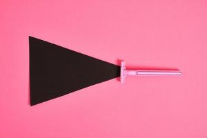 pink plastic disposable razor and black paper triangle on pink background photo