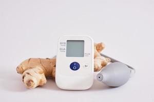 blood pressure monitor and ginger root on gray background photo