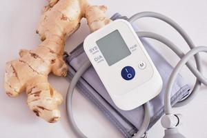 blood pressure monitor and ginger root on gray background photo