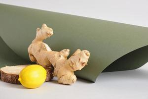 ginger root, lemon and wooden stand on gray and green background photo