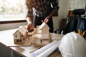Close up of male architect hands making model house. Man architect working in office. photo