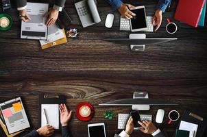 Top view of business Group of Multiethnic Busy People meeting with other in modern office with laptop computer, smartphone, tablet, coffee and document on table. photo