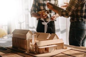 Scale model house on table with architects. Two architects making architectural model in office together. to form a new buildin photo