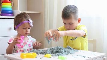 Boy and girl in the nursery at the table playing with kinetic sand video