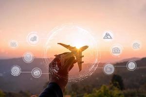 Hand holding a miniature airplane with the mountain view at sunrise, Summer vacation and travel planning icon and diagram concept photo