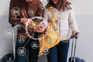 viajero de pareja joven con equipaje y mochila usando un teléfono inteligente para encontrar información y planificar viajes en el aeropuerto, concepto de planificación de viajes con iconos y diagrama foto