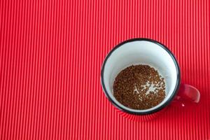 instant coffee in a mug on a red background, close up, top view photo