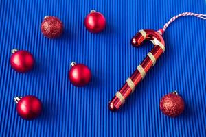 juguete de navidad en forma de bola roja y piruleta roja en forma de gancho sobre un fondo azul. foto