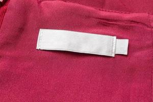 Blank white laundry care clothes label on red fabric texture background photo