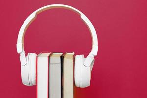 Audio book concept with headphones and a book on a viva magenta background. Listening to a book. photo